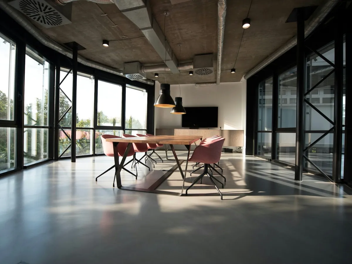 A bright open office with a glass wall and concrete ceiling